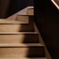 ####Das Treppenhaus besticht durch die Kombination von natürlichem Holz und Travertin, eleganter Beleuchtung und dezenten Messingelementen, die Funktionalität und Design vereinen. Die individuell gefertigten Bischofsmützen ergänzen das Erscheinungsbild harmonisch.
