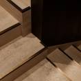 ####Das Treppenhaus besticht durch die Kombination von natürlichem Holz und Travertin, eleganter Beleuchtung und dezenten Messingelementen, die Funktionalität und Design vereinen. Die individuell gefertigten Bischofsmützen ergänzen das Erscheinungsbild harmonisch.