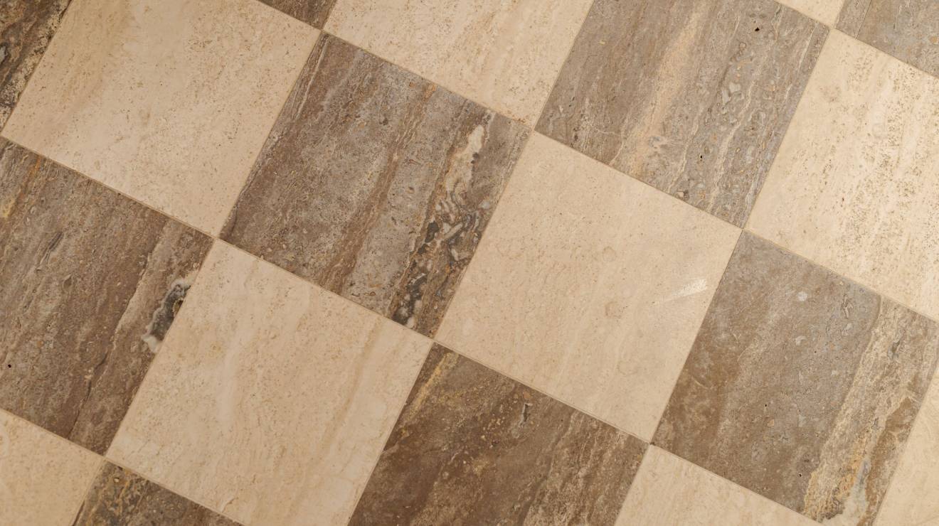 ####Im WC-Bereich des Concept Stores wurde wiederum die Diagonalverlegung von den WCs im Untergeschoss übernommen. Anders dazu wurde hier jedoch auf die beige- und braunfarbenen Travertine Romano Classico und Titanium gesetzt. In handwerklicher Präzision verlegt, ergibt sich somit ein Muster, das Wärme, Natürlichkeit und Wohlbefinden ausstrahlt. Die, in beigem Travertin gehaltene Rückwand, als auch der Waschtisch runden das Gesamtkonzept perfekt ab. Durch die metallische Badezimmerausstattung entsteht ein Kontrast, der sich perfekt in die Farbgebung des Raumes integriert.