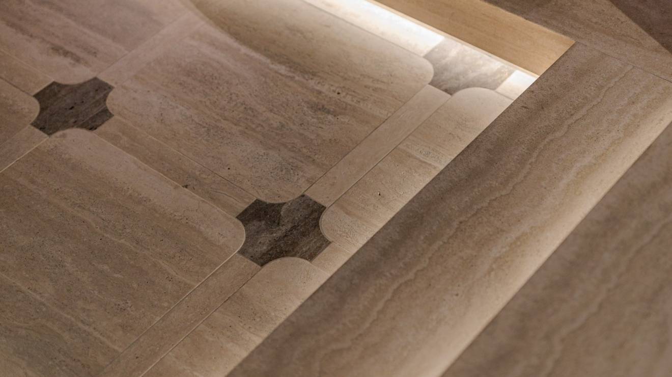 ####Im Untergeschoss verschmelzen beige- und braunfarbener Travertin, edles Nussholz, metallische Strukturen und feines Leder zu einer harmonischen Einheit. Das Zusammenspiel aus klaren Linien und sanft gerundeten Formen prägt dabei maßgeblich die Atmosphäre und das Geschehen. Angrenzend zur Tanzfläche wurden insgesamt vier massive Sekttische, bestehend aus Travertin Romano Classico (Unterteil) und Travertin Titanium (Oberteil) positioniert, die zum entspannten Verweilen einladen. In Präzisionsarbeit wurden in die Sekttische Vertiefungen sowie konische Aussparungen für Sektkübel eingearbeitet.
