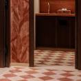 ####Der WC-Bereich bringt Farbe in die Räumlichkeiten. Die rotfarbenen Akzente setzen einen markanten, aber harmonischen Kontrast zur beige-braunen Farbgebung des Barbereichs. Bestehend aus knapp 60 verschiedenen Teilen, erzeugt die aufwendige Diagonalverlegung des Bodenbelags durch die Farbkombination von rotem und beigen Travertin ein mediterranes Flair. <p>
Abgerundet wird das Erscheinungsbild des Bereichs durch die ebenfalls in rotem Travertin ausgeführten Wandplatten und Waschtische. Letztere wurden, um dem massiven Stil der Architektur gerecht zu werden, aus einzelnen, in Gehrung verleimten Platten gefertigt. <p>